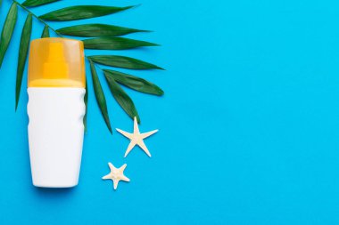 Güneş kremi şişesi. Güneş korumalı krem ve tropik yeşil yapraklı deniz kabukları olan bir şişe..