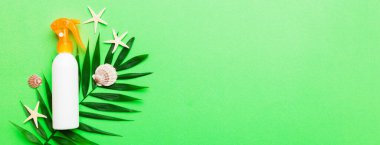 Güneş kremi şişesi. Güneş korumalı krem ve tropik yeşil yapraklı deniz kabukları olan bir şişe..