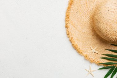 Summer holidays. Summer concept with straw hat and tropical leaf. Flat lay, top view, copy space.