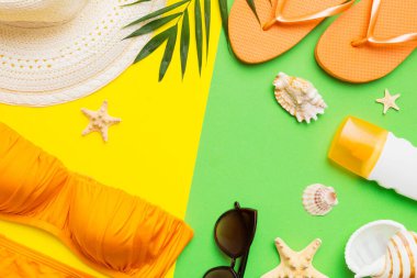 Woman swimwear and beach accessories flat lay top view on colored background Summer travel concept. bikini swimsuit, straw hat and seasheels. Copy space Top view.