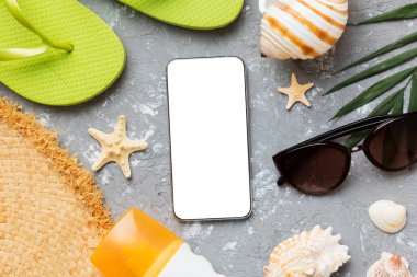 Flat lay composition with Phone and beach accessories on colored background. Smartphone with blank screen mock up with copy space.