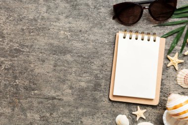Blank writing book with summer beach accessories on background, copy space. Flat lay with copy space.
