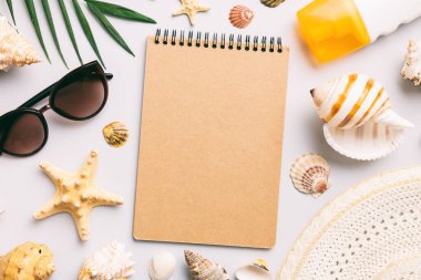 Blank writing book with summer beach accessories on background, copy space. Flat lay with copy space.