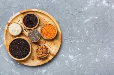 Smal Bowl 'da renkli arka planda çeşitli süper yiyecekler. Pirinç, chia, kinoa, mercimek, fındık, susam tohumu, badem gibi süper yiyecekler. en üstteki görünüm.