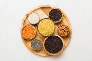 Smal Bowl 'da renkli arka planda çeşitli süper yiyecekler. Pirinç, chia, kinoa, mercimek, fındık, susam tohumu, badem gibi süper yiyecekler. en üstteki görünüm.