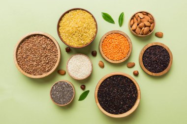 Smal Bowl 'da renkli arka planda çeşitli süper yiyecekler. Pirinç, chia, kinoa, mercimek, fındık, susam tohumu, badem gibi süper yiyecekler. üst görünüm kopyalama alanı.