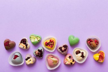 chocolate sweets in the form of a heart with fruits and nuts on a colored background. top view with space for text, holiday concept.