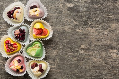 chocolate sweets in the form of a heart with fruits and nuts on a colored background. top view with space for text, holiday concept.