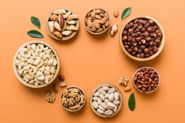 mixed nuts in wooden bowl. Mix of various nuts on colored background. pistachios, cashews, walnuts, hazelnuts, peanuts and brazil nuts.