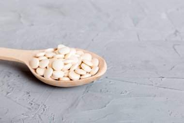 Renkli arka planda bir yığın beyaz hap. Tabletler masaya saçılmış. Kırmızı yumuşak jelatin kapsül yığını. Vitaminler ve beslenme takviyeleri konsepti.