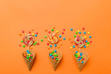 waffle cone full of assorted traditional candies falling out on colored background with copy space. Happy Holidays sale concept.
