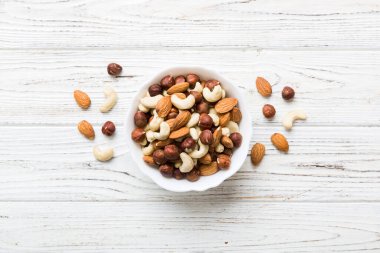 Renkli masadaki ahşap kasede fındık çeşitleri. Ceviz, fındık, ceviz, badem. Fındık Üst görünümü ile kopyalama alanını karıştır.