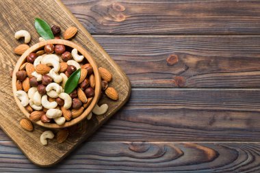 Renkli masadaki ahşap kasede fındık çeşitleri. Ceviz, fındık, ceviz, badem. Fındık Üst görünümü ile kopyalama alanını karıştır.