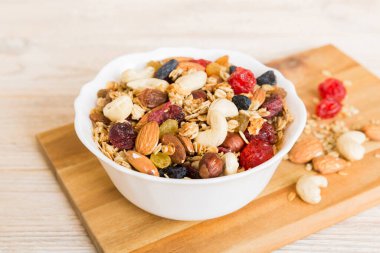Sağlıklı bir kahvaltı hazırlıyorum. Bir kasede çeşitli kurutulmuş meyve ve fındıklı granola. Sağlıklı tatlı kavramı. Düz konum, kopyalama alanı olan üst görünüm.