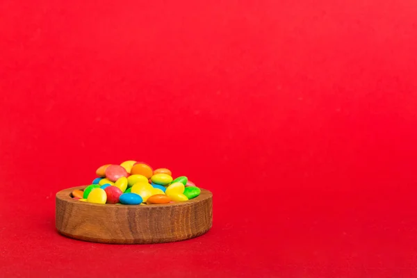 Multicolored candies in a bowl on a colored background. birthday and holiday concept. Top view with copy space.