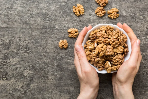 stock image Woman hands holding a wooden bowl with walnut nuts. Healthy food and snack. Vegetarian snacks of different nuts.