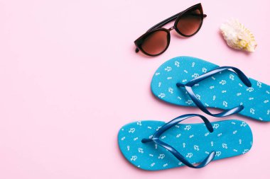 Yaz yolculuğu konsepti. Parmak arası terlikler, güneş gözlükleri ve beyaz üzerine deniz yıldızı. Renkli arkaplanda üst görünüm.