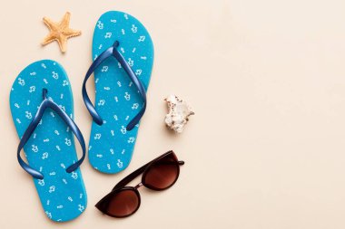 Yaz yolculuğu konsepti. Parmak arası terlikler, güneş gözlükleri ve beyaz üzerine deniz yıldızı. Renkli arkaplanda üst görünüm.
