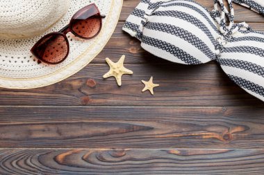 Woman swimwear and beach accessories flat lay top view on colored background Summer travel concept. bikini swimsuit, straw hat and seasheels. Copy space Top view.