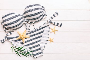 Woman swimwear and beach accessories flat lay top view on colored background Summer travel concept. bikini swimsuit, straw hat and seasheels. Copy space Top view.