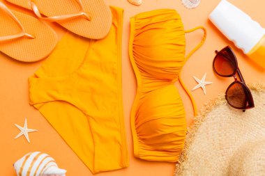 Kadın mayo ve plaj aksesuarları renkli arka plan yaz seyahati konseptine düz bir görünüm kazandırıyordu. Bikini mayo, hasır şapka ve deniz topuklu ayakkabı. Üst görünümü kopyala.