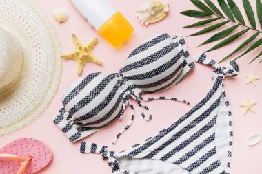 Kadın mayo ve plaj aksesuarları renkli arka plan yaz seyahati konseptine düz bir görünüm kazandırıyordu. Bikini mayo, hasır şapka ve deniz topuklu ayakkabı. Üst görünümü kopyala.