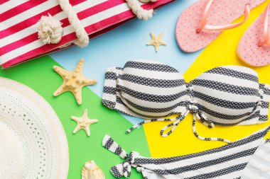 Woman swimwear and beach accessories flat lay top view on colored background Summer travel concept. bikini swimsuit, straw hat and seasheels. Copy space Top view.