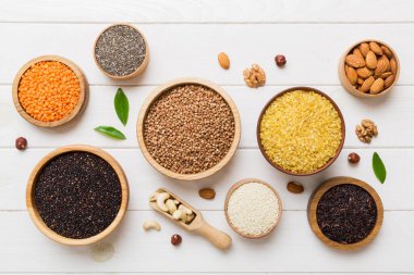 Smal Bowl 'da renkli arka planda çeşitli süper yiyecekler. Pirinç, chia, kinoa, mercimek, fındık, susam tohumu, badem gibi süper yiyecekler. üst görünüm kopyalama alanı.