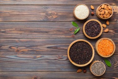 Smal Bowl 'da renkli arka planda çeşitli süper yiyecekler. Pirinç, chia, kinoa, mercimek, fındık, susam tohumu, badem gibi süper yiyecekler. üst görünüm kopyalama alanı.