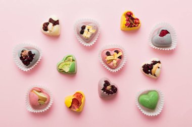 chocolate sweets in the form of a heart with fruits and nuts on a colored background. top view with space for text, holiday concept.