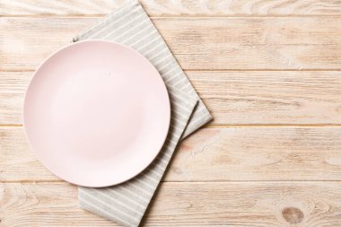 Renkli arka planda üst manzara. Yemek için masa örtüsü üzerine yuvarlak pembe tabak. Tasarımınız için boşluk olan peçeteye boş tabak.