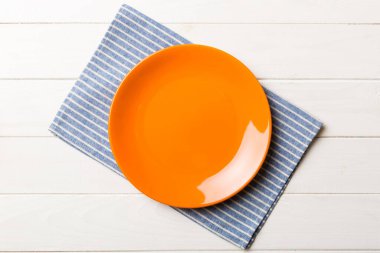 Renkli arka planda üst görünüm yiyecek için masa örtüsü üzerindeki boş yuvarlak kırmızı tabak. Tasarımınız için boşluk olan peçeteye boş tabak.