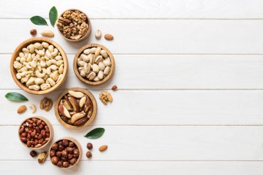 mixed nuts in wooden bowl. Mix of various nuts on colored background. pistachios, cashews, walnuts, hazelnuts, peanuts and brazil nuts.