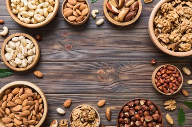 mixed nuts in wooden bowl. Mix of various nuts on colored background. pistachios, cashews, walnuts, hazelnuts, peanuts and brazil nuts.