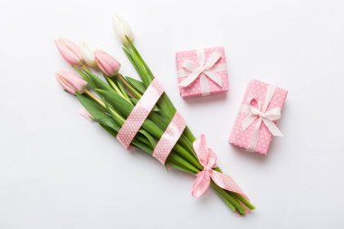 Pembe lale çiçekleri ve hediye ya da renkli masa arkaplanındaki hediye kutusu. Anneler günü, doğum günü, kadınlar günü, kutlama konsepti. Metin üstü görünümü için boşluk.