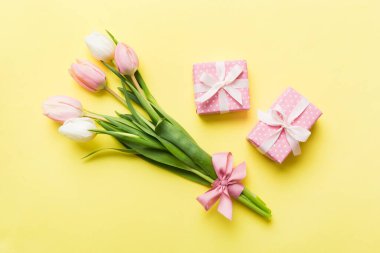 Pembe lale çiçekleri ve hediye ya da renkli masa arkaplanındaki hediye kutusu. Anneler günü, doğum günü, kadınlar günü, kutlama konsepti. Metin üstü görünümü için boşluk.