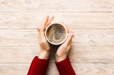 Renkli arka planda bir fincan kahve tutan minimalist stil bir kadın. Düz yerde, kapuçino bardağının üstünde. Metin için boş yer, kopyalama alanı. Kahve bağımlılığı. Üst manzara, düz uzanma.