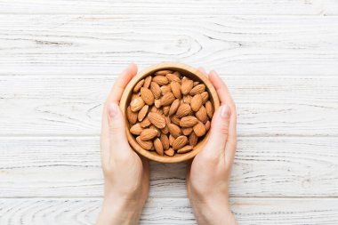 Kadın elleri, badem fıstıklı ahşap bir kase tutuyor. Sağlıklı yemek ve atıştırmalık. Farklı fındıklı vejetaryen atıştırmalıkları..