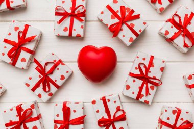 gift box with red bow and red heart on colored background . Top view. Flat lay.