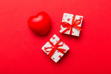gift box with red bow and red heart on colored background . Top view. Flat lay.