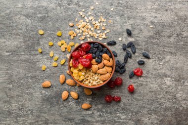 Sağlıklı bir kahvaltı hazırlıyorum. Bir kasede çeşitli kurutulmuş meyve ve fındıklı granola. Sağlıklı tatlı kavramı. Düz konum, kopyalama alanı olan üst görünüm.