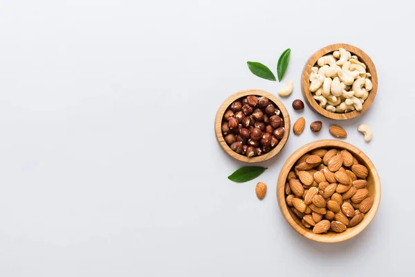 Stock image Assortment of nuts in wooden bowl on colored table. Cashew, hazelnuts, walnuts, almonds. Mix of nuts Top view with copy space.