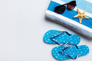 Yaz yolculuğu konsepti. Parmak arası terlikler, güneş gözlükleri ve beyaz üzerine deniz yıldızı. Renkli arkaplanda üst görünüm.