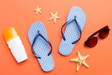 Yaz yolculuğu konsepti. Parmak arası terlikler, güneş gözlükleri ve beyaz üzerine deniz yıldızı. Renkli arkaplanda üst görünüm.