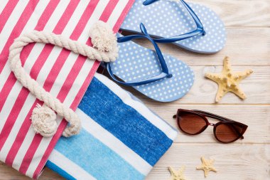 Plaj aksesuarları renkli arka plan yaz seyahati konseptinde düz bir görünüm sergiliyordu. İçinde deniz yıldızı ve deniz kabuğu olan bir çanta. Üst görünüm.