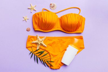 Kadın mayo ve plaj aksesuarları renkli arka plan yaz seyahati konseptine düz bir görünüm kazandırıyordu. Bikini mayo, hasır şapka ve deniz topuklu ayakkabı. Üst görünümü kopyala.