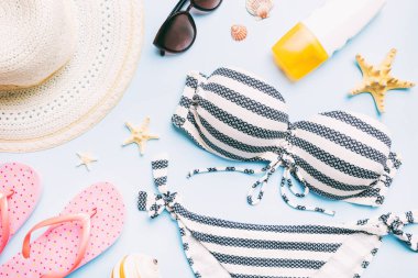 Woman swimwear and beach accessories flat lay top view on colored background Summer travel concept. bikini swimsuit, straw hat and seasheels. Copy space Top view.