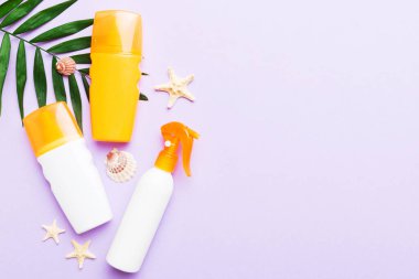Güneş kremi şişesi. Güneş korumalı krem ve tropik yeşil yapraklı deniz kabukları olan bir şişe..