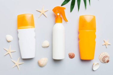 Güneş kremi şişesi. Güneş korumalı krem ve tropik yeşil yapraklı deniz kabukları olan bir şişe..