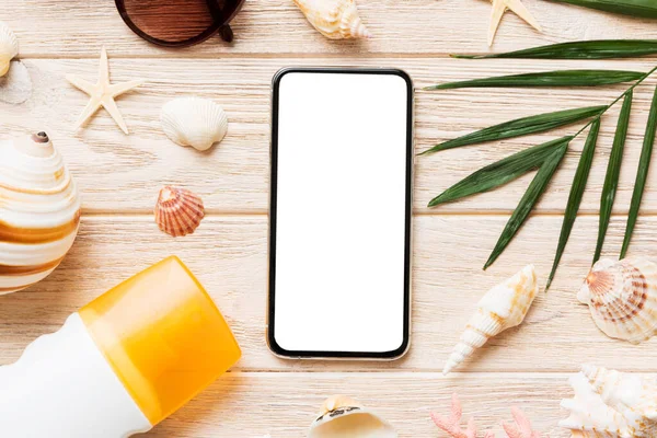 Renkli arka planda telefon ve plaj aksesuarları olan düz kompozisyon. Boş ekran ile akıllı telefon kopyalama alanı ile taklit.